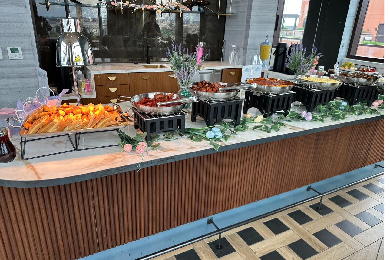 Catered buffet with modern black chafers and seasonal florals set up by B Hospitality Group