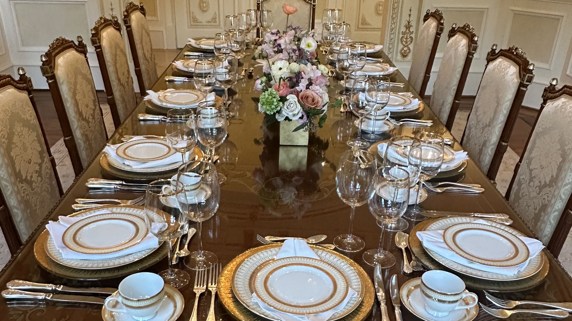Formal dining table set with gold rimmed china, crystal glassware and fresh floral centrepieces for a private dinner catered by B Hospitality Group